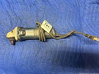 Bosch angle grinder with power cord coiled around it, showing entire tool on a blue padded surface.