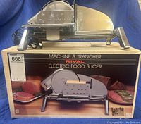 Rival electric food slicer on top of original box showing front view and brand label.