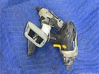 Two cordless impact wrenches on blue padded cloth. One Mastercraft with black/gray body and yellow trigger, one Maximum also cordless, both heavily used without batteries.