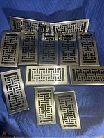 Set of 12 nickel plated floor vents showing front grille design and arranged on blanket