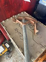 Full view of the metal pipe bender showing long handle and curved bending arm resting on a plastic surface.