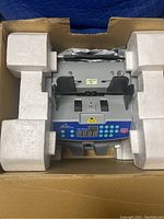 Front view of the cash bill counter inside foam packaging within the box.