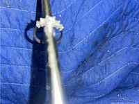 Image of five assorted rings including a distinctive $ Rsc ring displayed on metal rods over a blue quilted fabric.