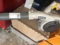 Side view of Ryobi leaf blower showing blower tube and Ryobi branding.