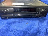 Front view of Technics SA-EX100 stereo receiver showing tuning controls, preset buttons, volume knob, and display.