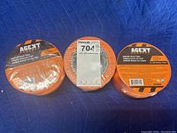 Three rolls of Agent brand AM600 orange vinyl tape, packaging visible with product labels and branding