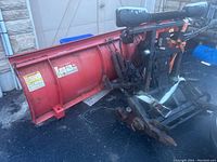 Front view of the red curved plow blade with hydraulic springs and mounting frame