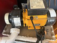 Top angled view displaying the yellow motor with a black electrical housing and white plumbing connectors.