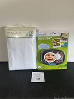 Overview of the lot showing the mattress protector sealed in plastic and the Brica DualSight baby car mirror in original packaging