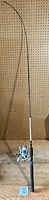 Full view of Shakespeare Synergy Steel fishing rod standing vertically with attached spinning reel and foam handle grip.