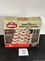 Front view of the Expert Grill Gas Grill Ceramic Briquettes 50 pack box showing branding, product image, and price tag.