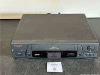 Front view of Magnasonic MVC 646 VHS recorder showing tape slot, control buttons, and digital display.