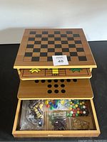 Multi game board with chess/checkers board on top, layered boards visible beneath showing other game layouts.