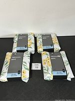 Lot of 4 Hometrends tablecloths neatly stacked, showing the product packaging with floral design and size labels.