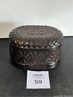 Front and top view of the carved wooden box showing detailed carvings and oval shape.