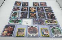 Photo of 22 wrestling cards laid out in three rows, featuring various wrestlers such as Hulk Hogan, Ric Flair, Sting, Manny Hart. Cards are protective sleeved and have colorful designs including some with numbers and star icons.