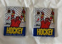 Front view of two sealed 1989-90 Topps hockey trading card packs lying on a white cloth surface, showing design and branding.