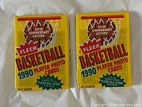 Front view of two sealed 1990 Fleer Basketball Player Photo Card packs in yellow packaging with red and green text and basketball graphic.