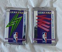 Front of two sealed 1991-92 Skybox NBA basketball card packs, showing distinct lightning bolt designs in green and red.