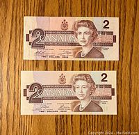 Fronts of two Canadian $2 bills showing Queen Elizabeth II portrait and denomination 2, dated 1986.