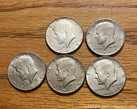 Obverse of five Kennedy Half Dollar coins showing JFK profile and dates 1967, 1968, two 1969, 1971