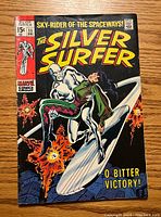 Front cover of The Silver Surfer #11 comic book showing the Silver Surfer and a man on his surfboard with explosions in the background, dated December, priced 15 cents.