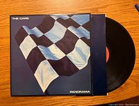 Front of vinyl record cover showing checkered flag design and partially visible vinyl record.