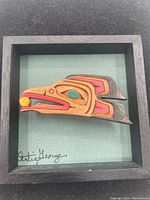 Duplicate front view showing carved raven profile detail and frame.