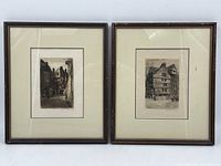 Photo of two framed vintage etching prints side by side showing architectural street scenes.