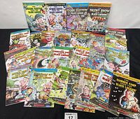 Photo showing full collection of 25 Black Lagoon Adventures books spread on black background, clear view of colorful illustrated covers