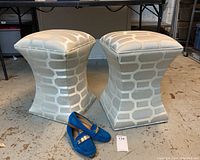 Pair of modern fabric ottoman stools with geometric pattern next to blue shoes for scale