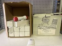 Box containing 12 white boxes with red and white flashlights on top, and the Series E Extraordinaire Bingo Set box beside it.