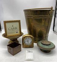 Photo showing all six items in the lot: large brass bucket, brass clock, decorative plate, small copper container, pedestal bowl with lid, and picture frame with placeholder insert