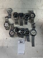 10 wristwatches assembled on table, showing various dial designs including chronographs and rectangular faces.