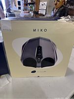 Front view of Miko Y2 Foot Massager box, showing image of device and brand name. Box shows wear and tear on top right corner.