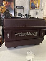 Closed JVC Video Movie VHS-C camcorder case showing JVC, Video Movie VHS-C branding and latches.