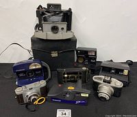 Wide front view of all cameras on black fabric with large black case behind them