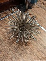 Photo of a metal sculpture shaped like a starburst made from hollow metal tubes arranged radially.