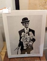 Framed black and white photo of an elderly man in a bowler hat and suit with dollar bills pinned to jacket, holding a cane.