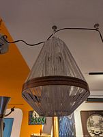 Pendant light hanging from ceiling, showing string shade and wooden band