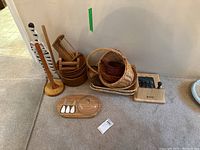 Full lot with baskets, wooden bowls, wooden trays, paper towel holders, and cheese serving set visible on the floor.