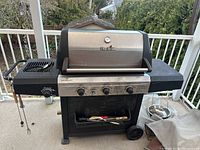 Full view of Char-Broil Performance Series gas BBQ grill on deck, showing grilling area, control panel with four knobs and side burner, wheels, and storage compartment with grilling tools.