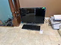 HP w2207h 22-inch computer monitor with the Acer keyboard placed in front of it on a tiled floor.
