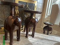 Wide view of three wooden elephant stands in front of fireplace, showing their graduated sizes