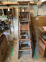 Tall wooden ladder with six steps, seen from front, showing wear and rustic condition