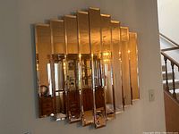 Full view of the rose gold tinted wall mirror composed of vertical mirror panels in a staggered design.