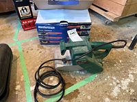 Photo of green Craftsman planer from side showing label and attached power cord with Mastercraft planer box in background.