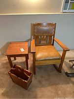 Front view of the Mission oak rocking chair with side table and magazine holder on carpeted floor under window.