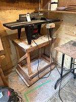 Photo of Craftsman router table with mounted router and wooden stand in shed environment.