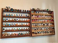 Two wooden thread holders mounted on wall filled with various thread spools of different colors and sizes.